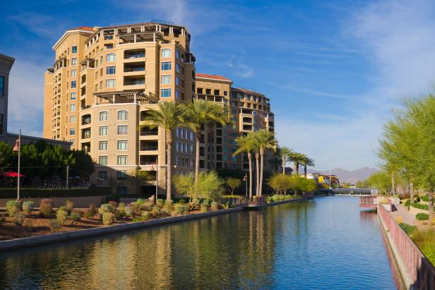 Waterfront Place condominium towers in Downtown Scottsdale, AZ (Phoenix metropolitan area) with the Arizona canal, palm trees, and riverfront walkways in the foreground.